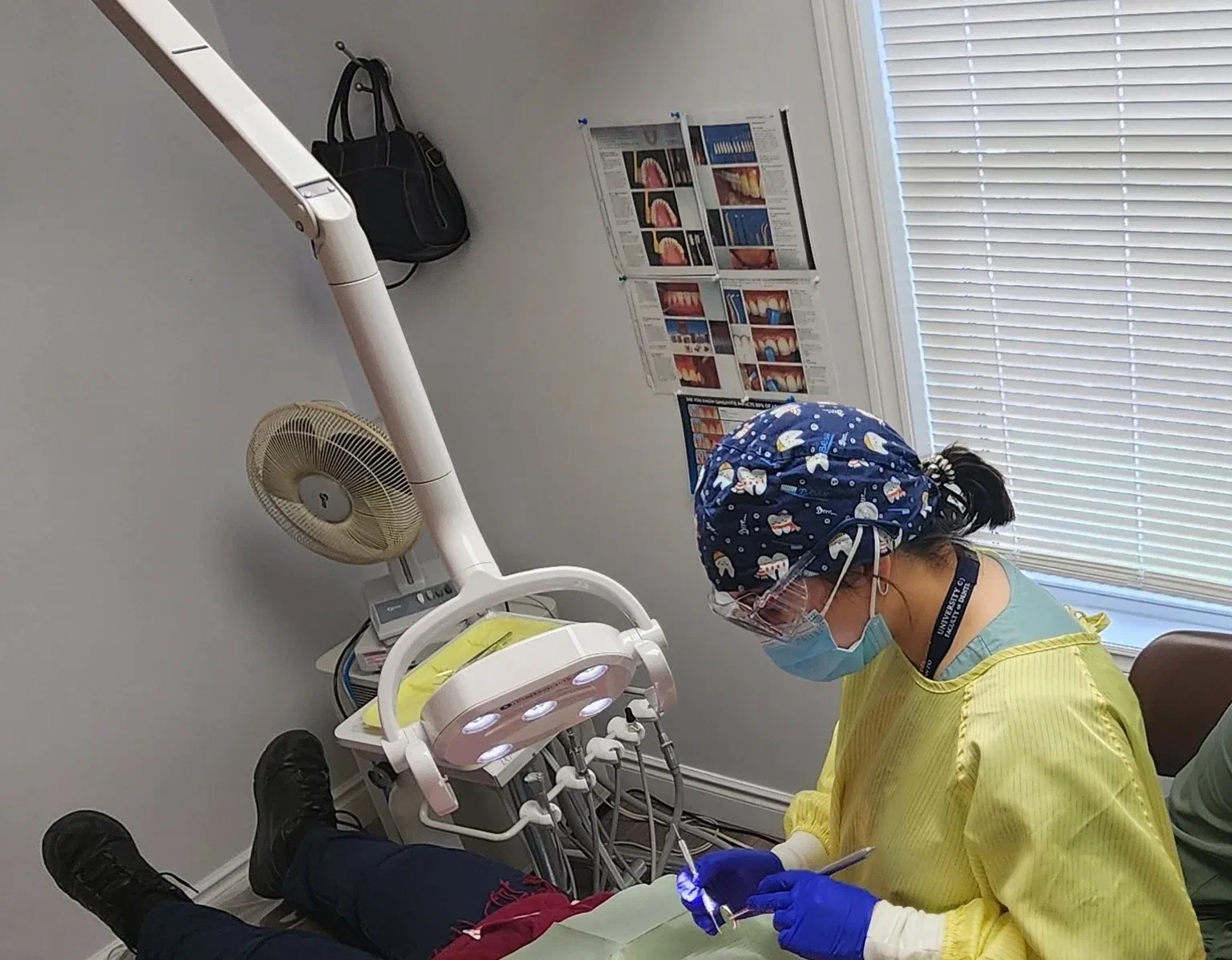 A dental clinician wearing a mask and gloves examines a patient
